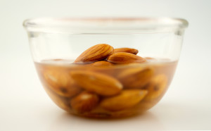Almonds being soaked in a clear bowl, isolated on white