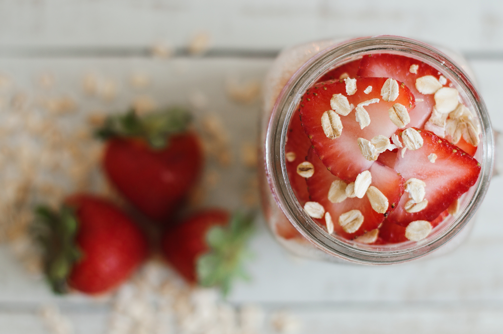 Overnight oats with strawberry, top view. Strawberry slices and whole grain cereal in a glass jar